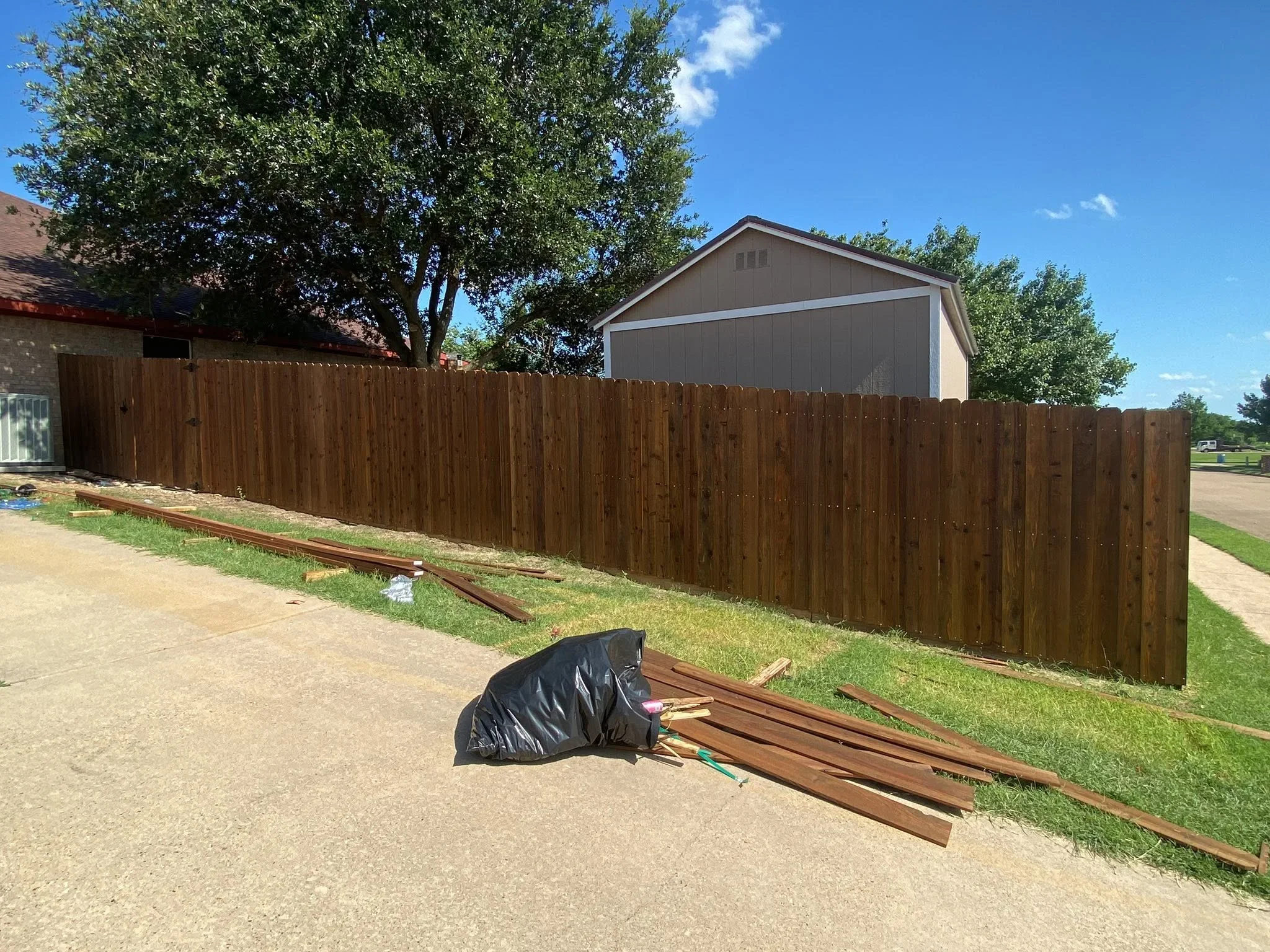 Stained wood privacy fence with vertical pickets installed along residential property line