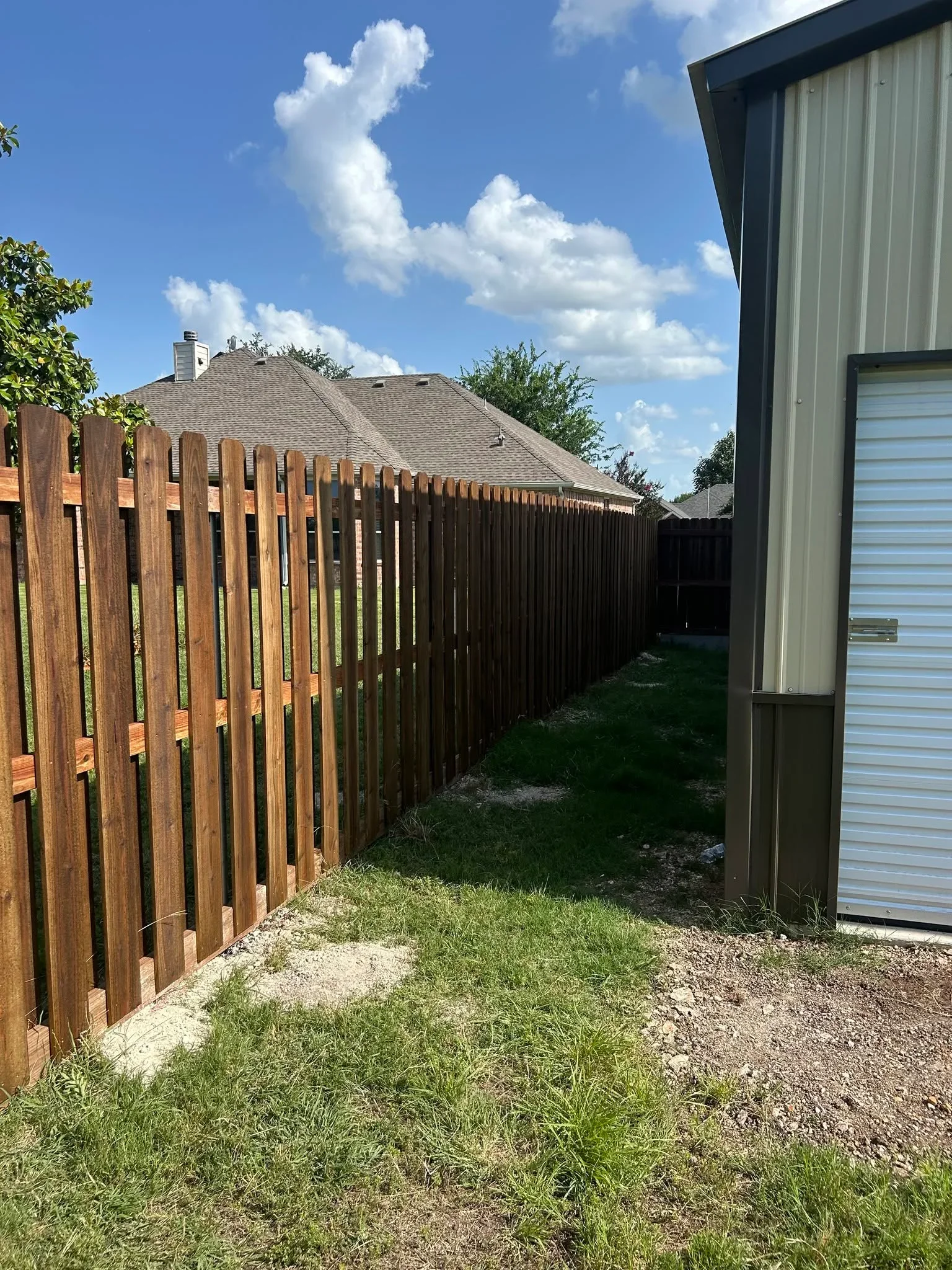 Vertical wood privacy fence with stained pickets along residential property line