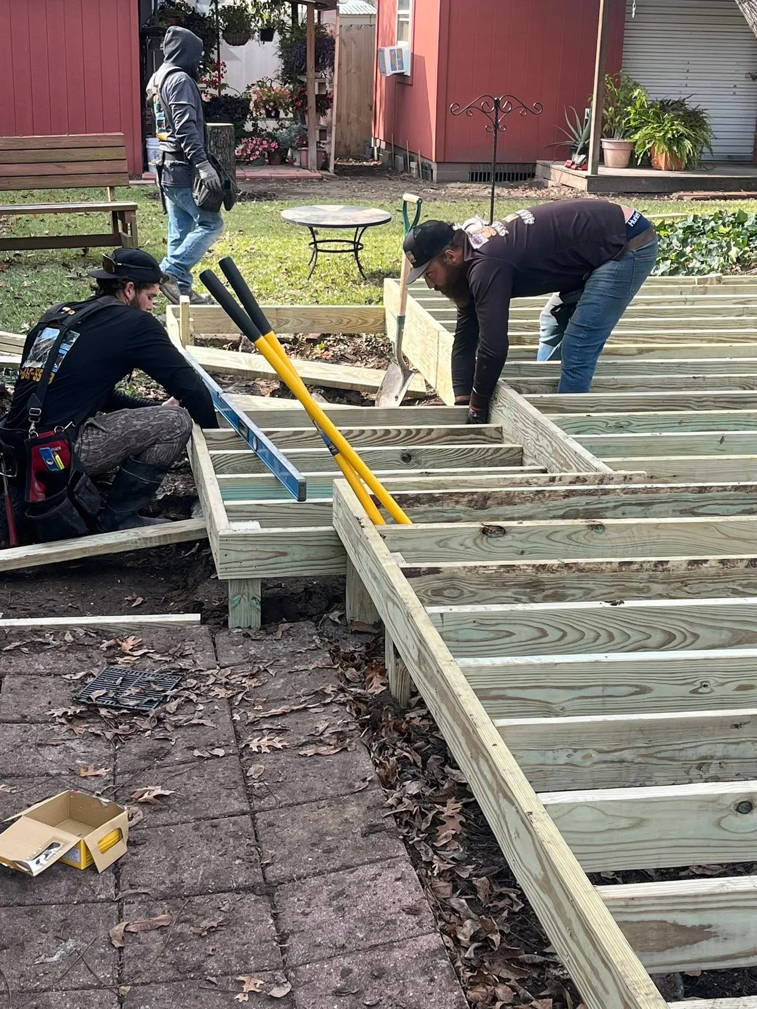 Pressure-treated lumber raised garden beds under construction with workers installing horizontal boards