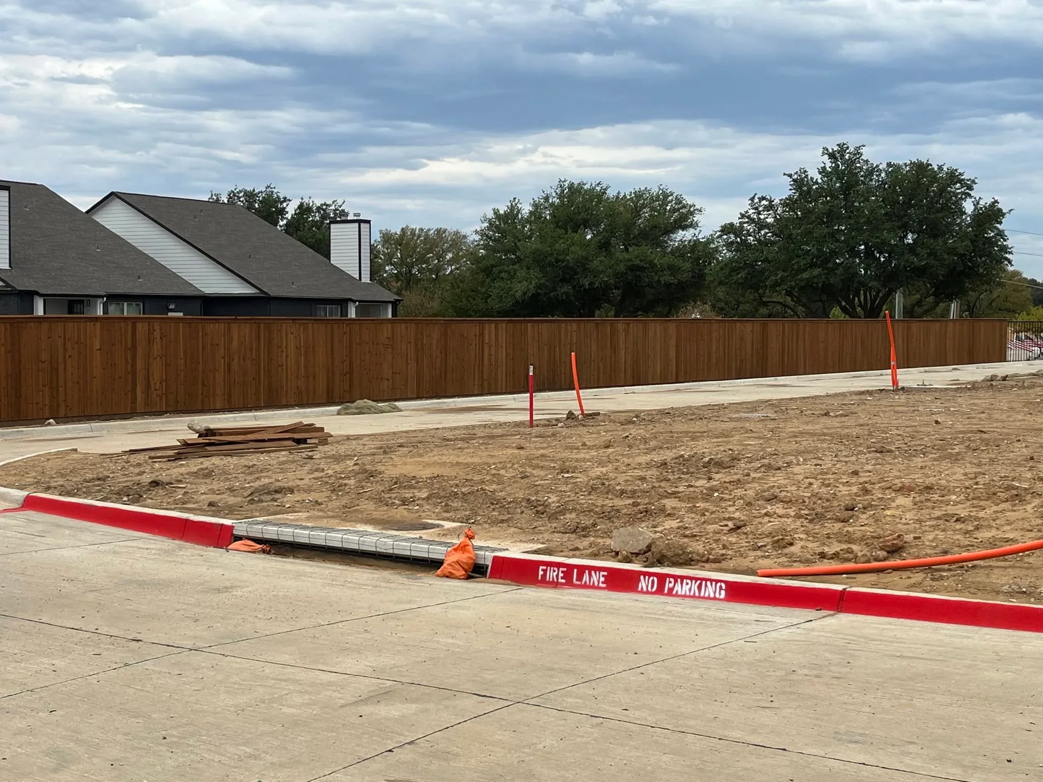 Tall wood privacy fence with vertical boards installed along residential driveway and property line