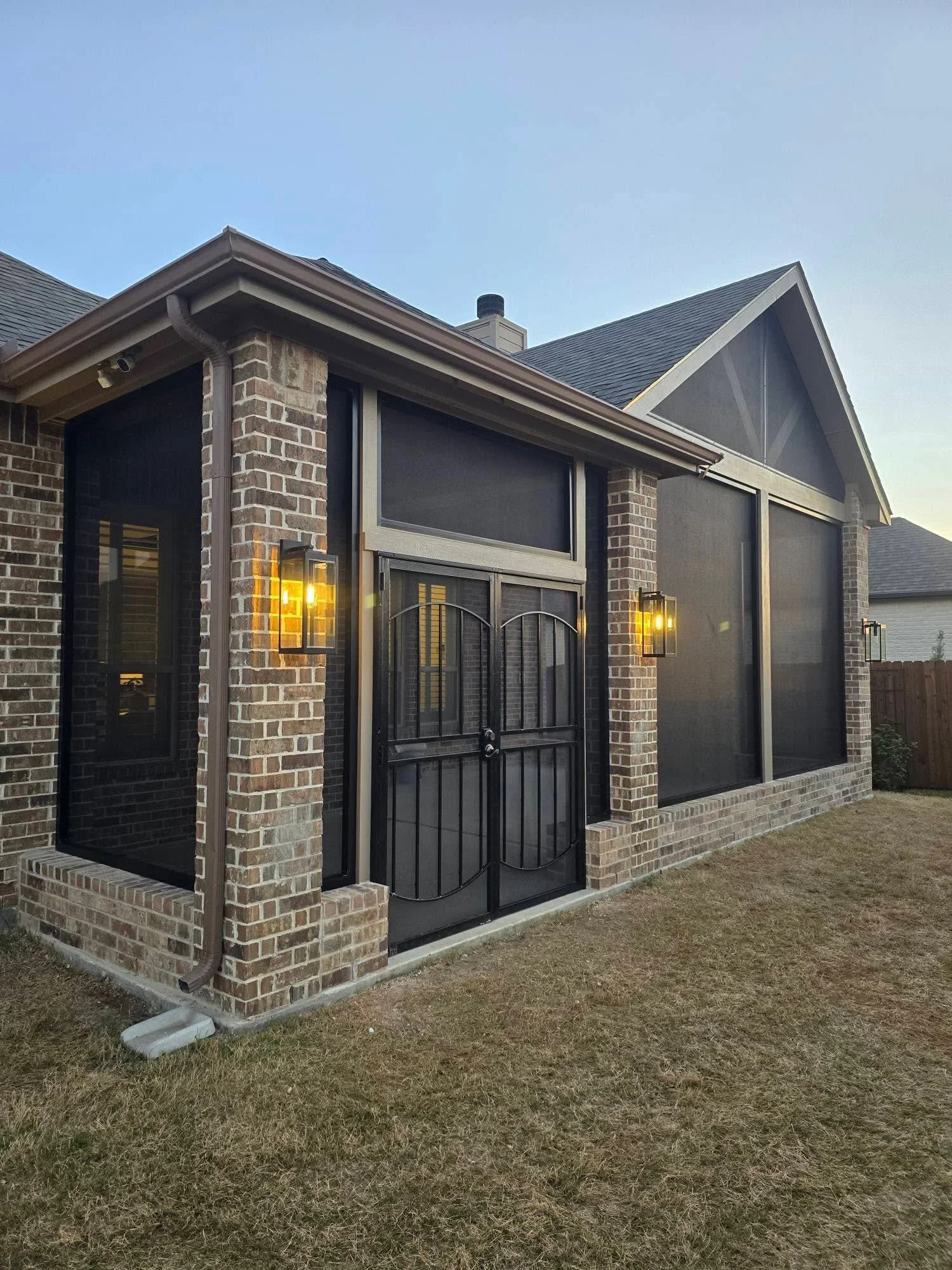 Black metal railings on brick patio enclosure with decorative scrollwork and gate