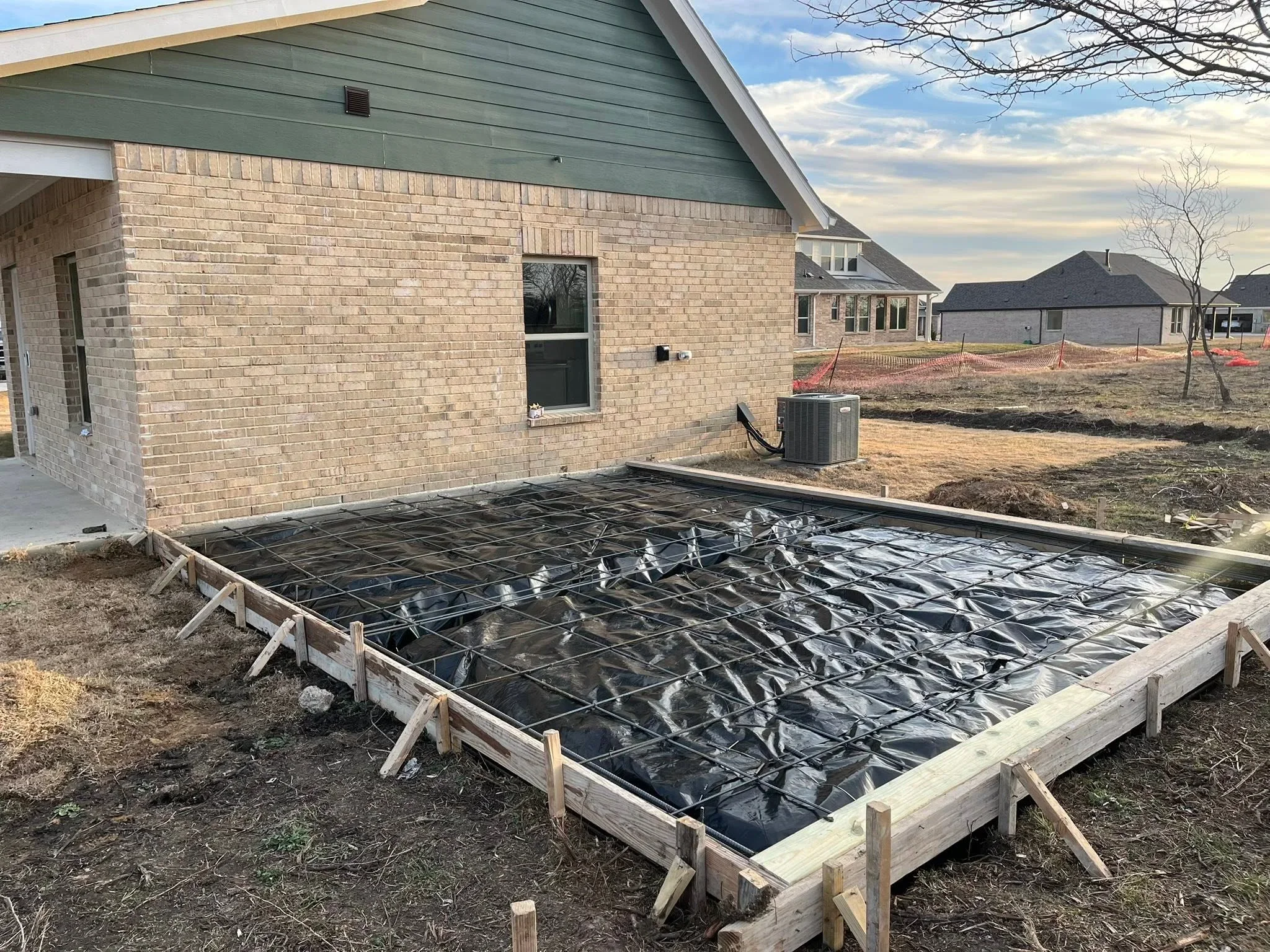Pressure-treated wood deck frame with black landscape fabric and rebar on residential property