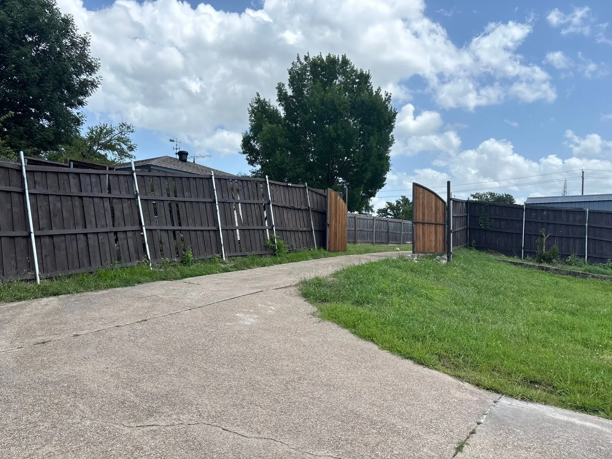 Wood and vinyl fence with white posts along driveway, wooden gates, residential property