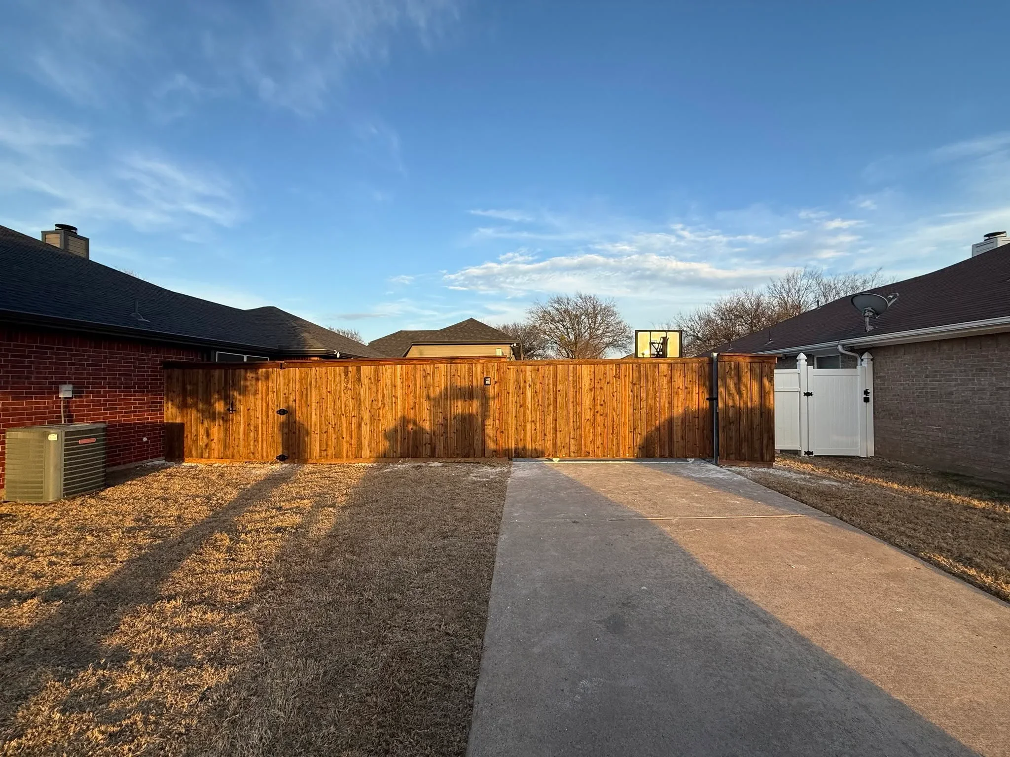 Stained wood privacy fence with vertical boards and double gate entry in residential backyard