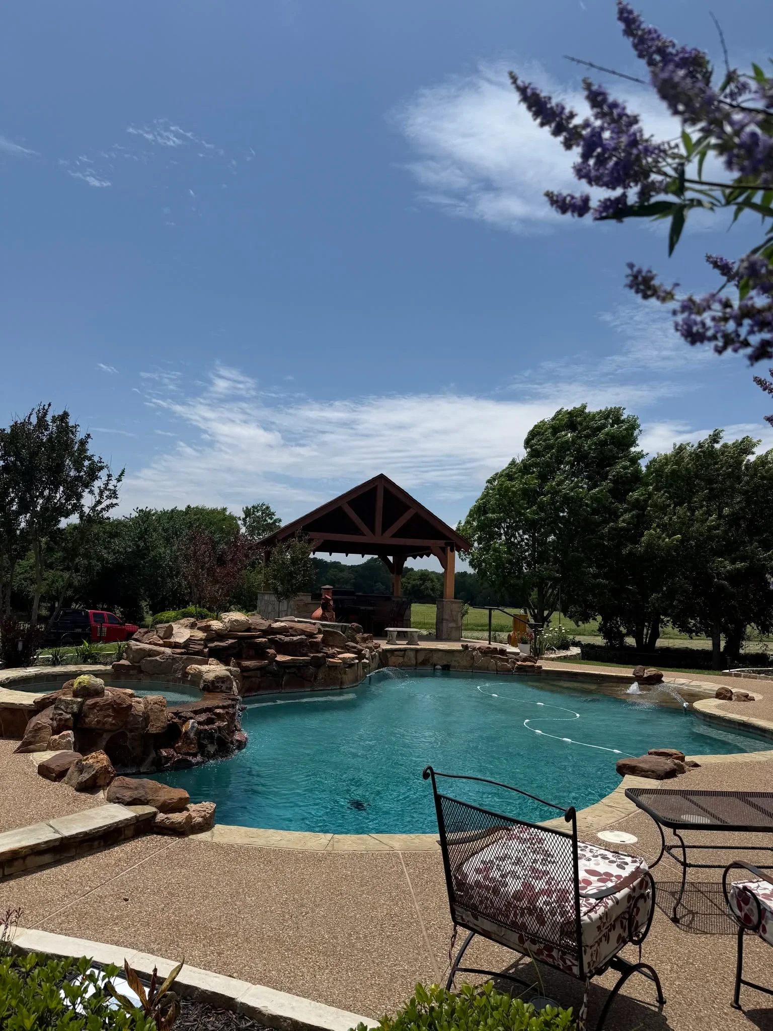 Stamped concrete pool deck with natural stone features and wooden pergola shade structure