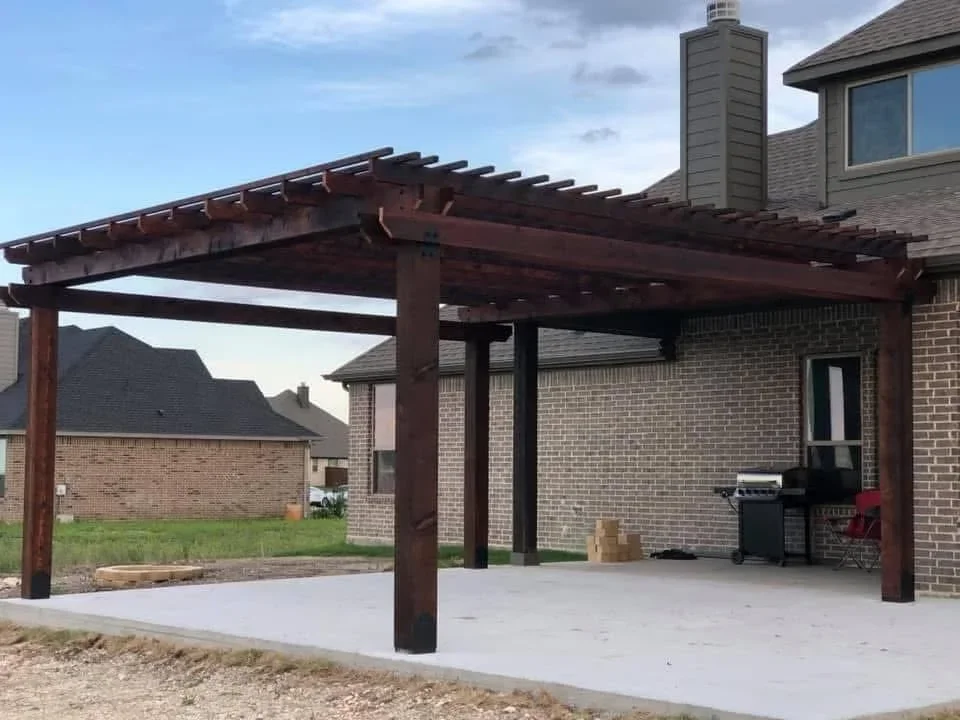 Dark stained wood pergola with timber posts and beams over concrete patio