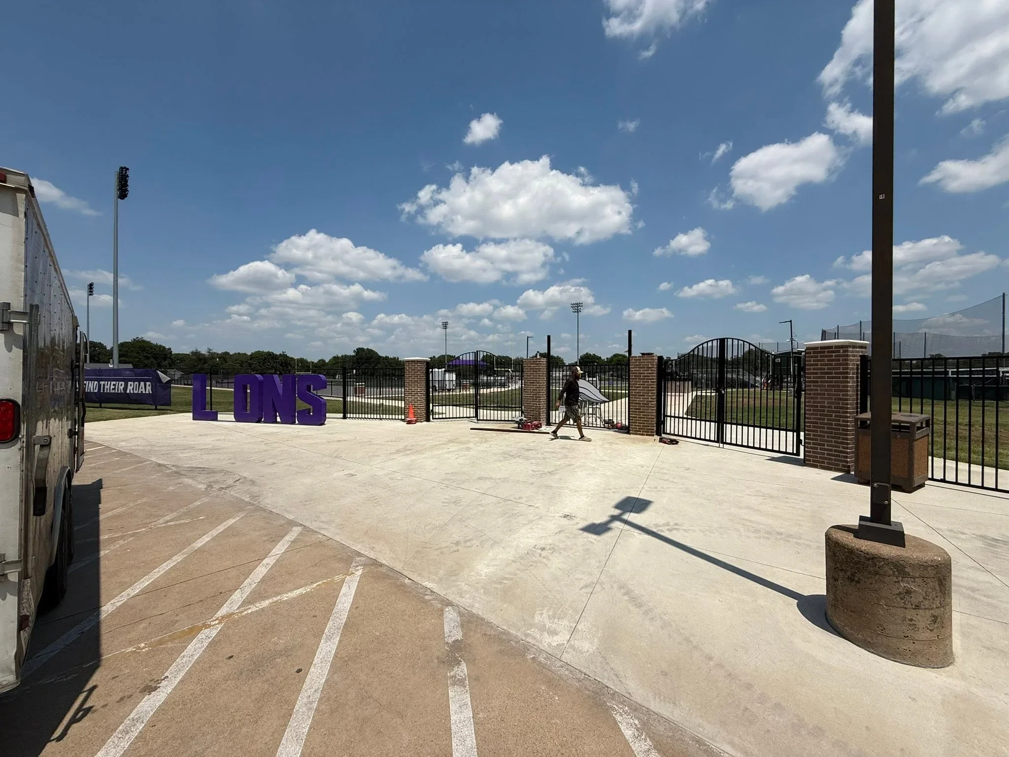 Black ornamental steel fence with brick pillars and arched gates at sports complex
