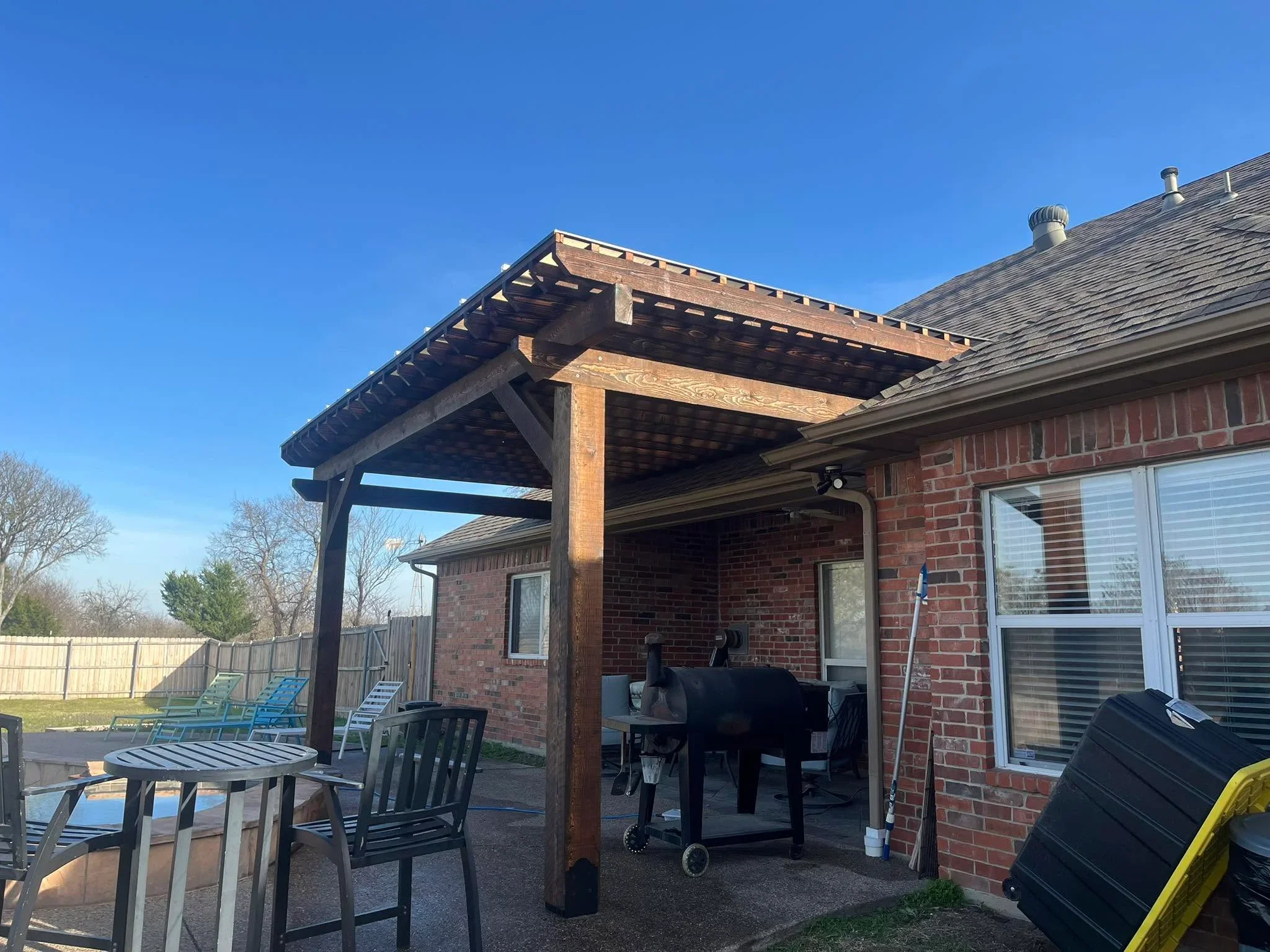 Stained timber pergola with lattice roof attached to brick home over patio