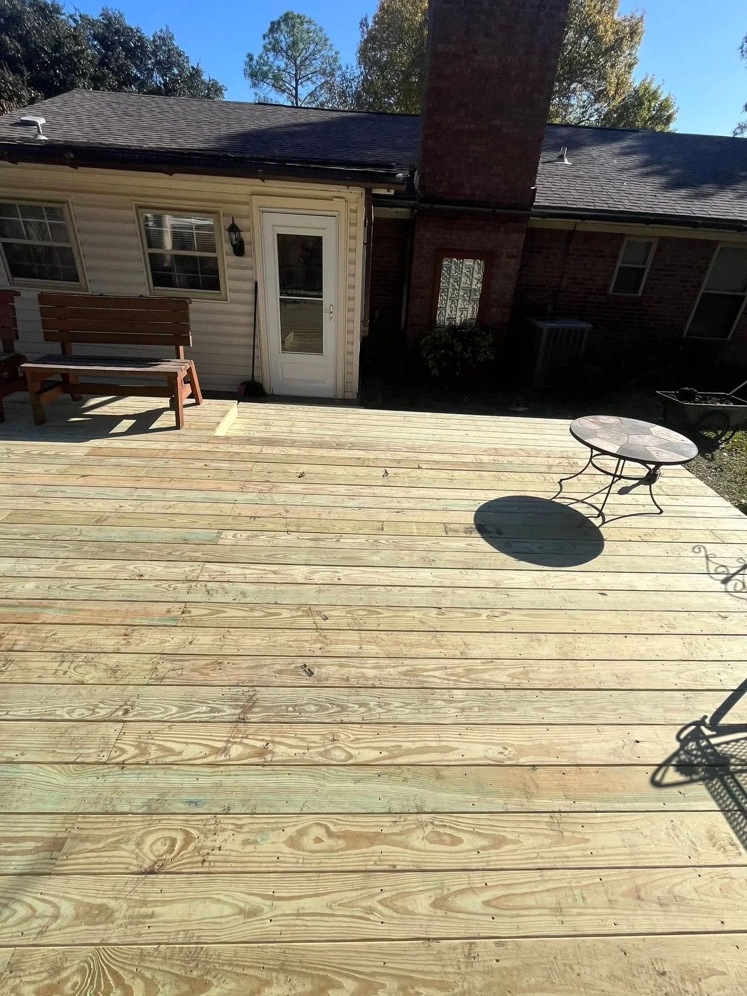 Newly constructed pressure-treated wood deck with horizontal boards and outdoor furniture