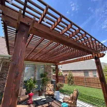 Stained wood pergola with lattice roof over paved patio adjacent to brick home
