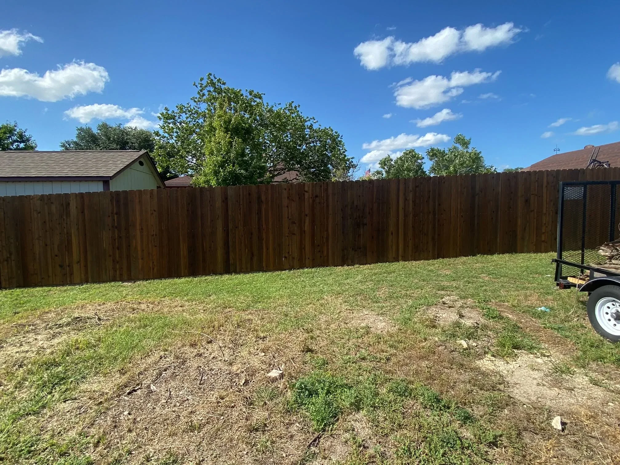 Tall wood privacy fence with vertical boards installed along residential backyard perimeter