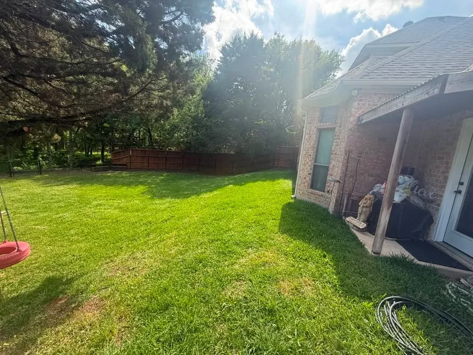 Stained wood privacy fence installed along residential backyard perimeter with brick home