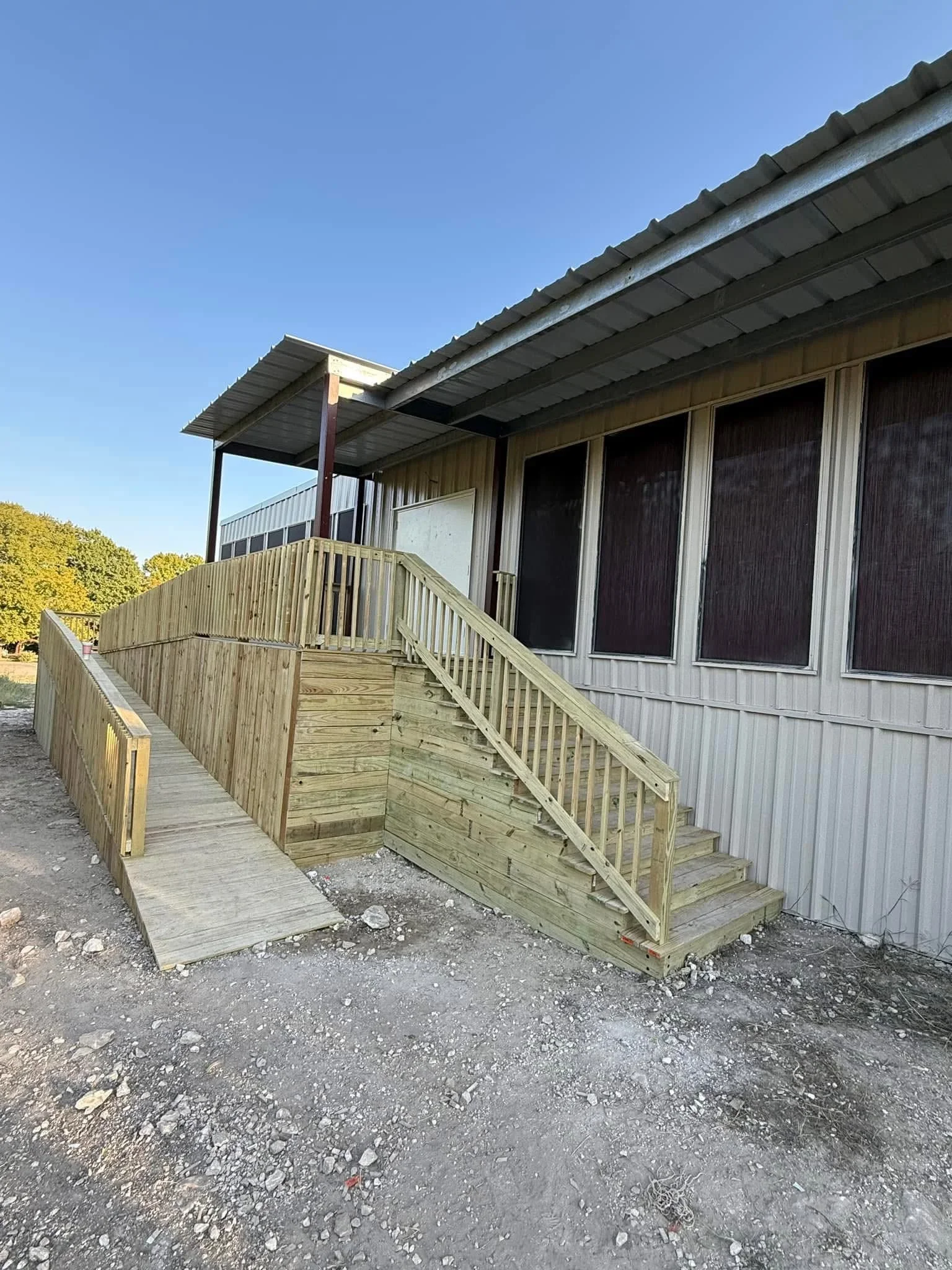 Pressure-treated wood deck with ramp, railings, and metal roof shelter structure