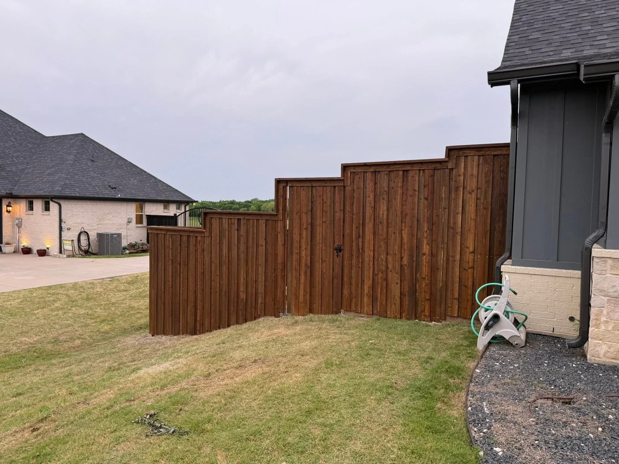 Stepped brown wood privacy fence with vertical boards on sloped residential property