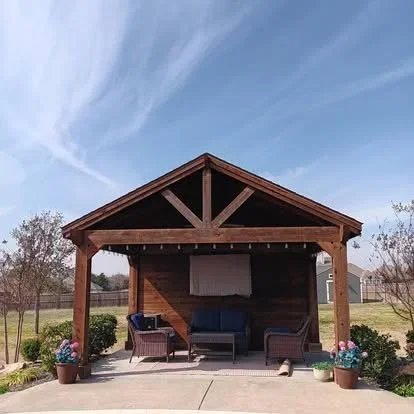 Timber frame pavilion with exposed beams, gable roof, concrete patio, and integrated seating
