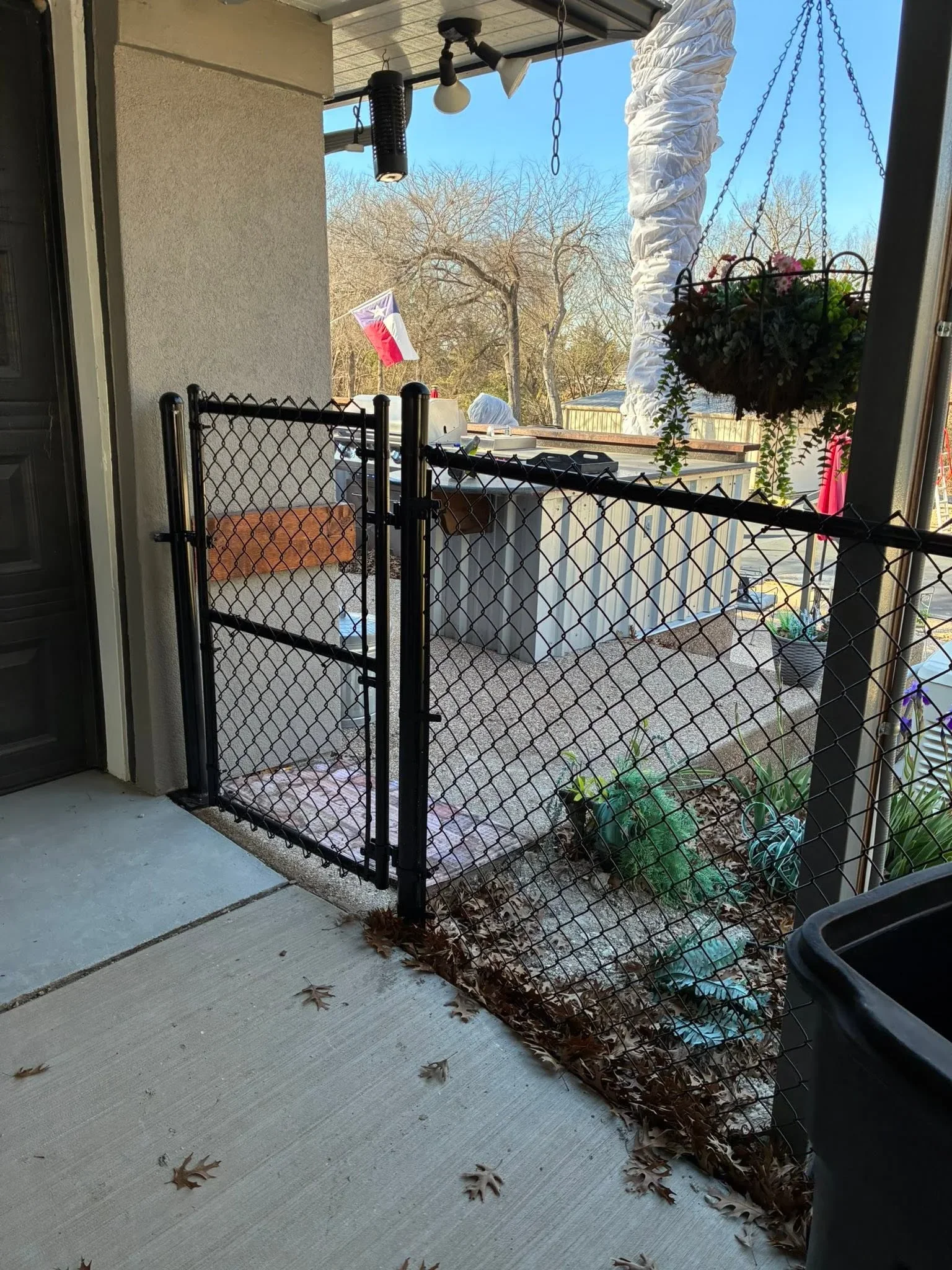 Black chain-link gate with hinges and latch on residential patio deck