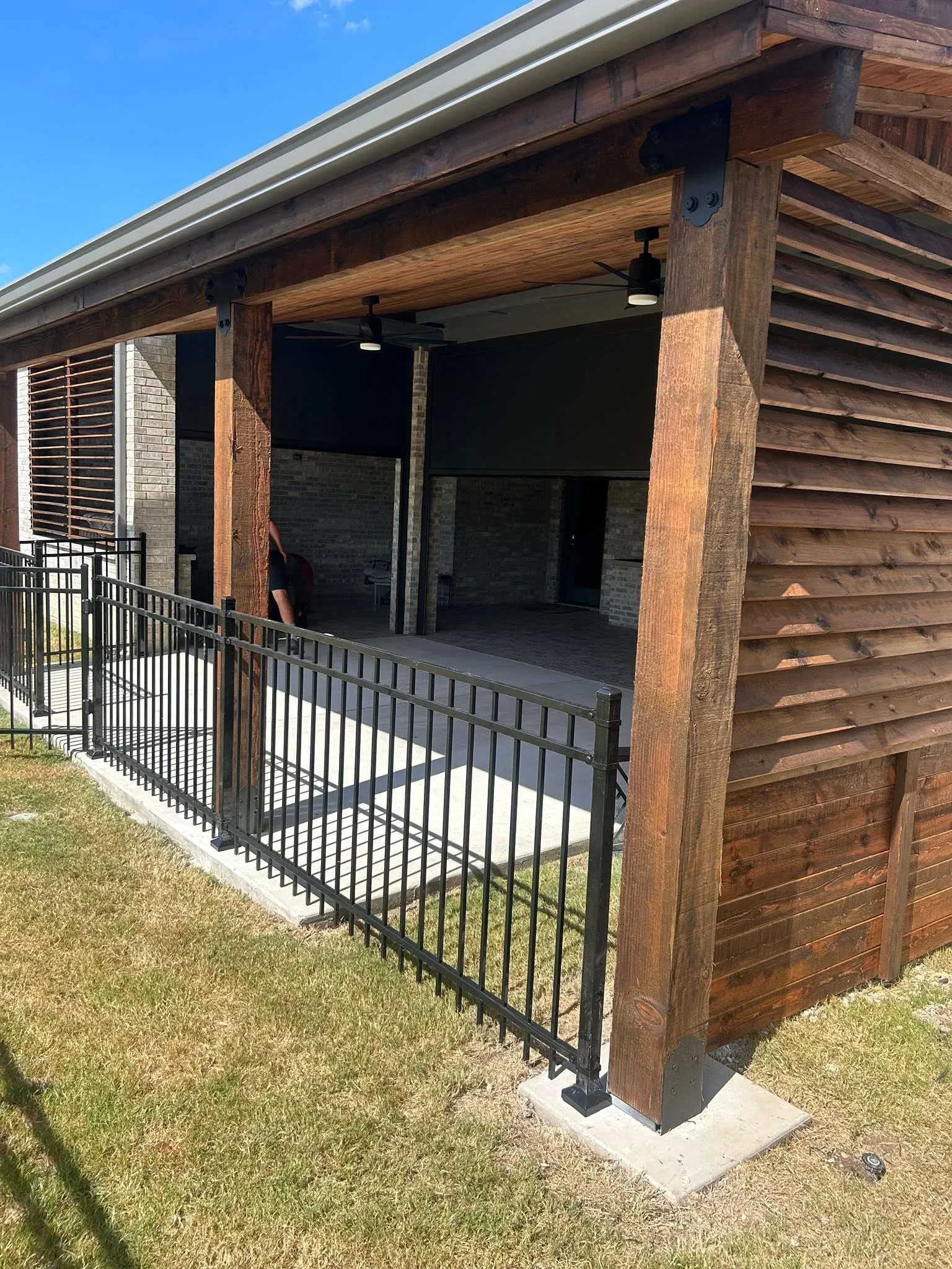 Composite deck with black metal railing, timber beams, and covered patio structure