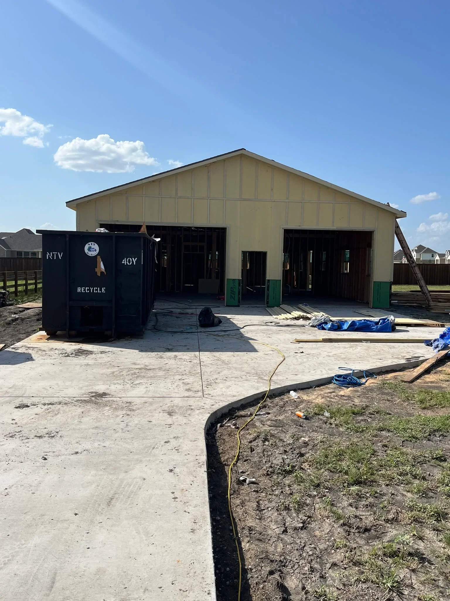 Concrete driveway with black edging and drainage installation at residential construction site