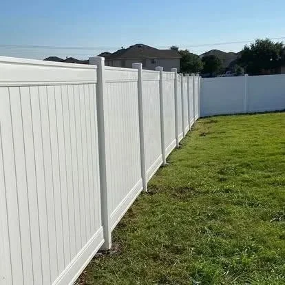 White vinyl privacy fence with vertical boards installed along residential property line