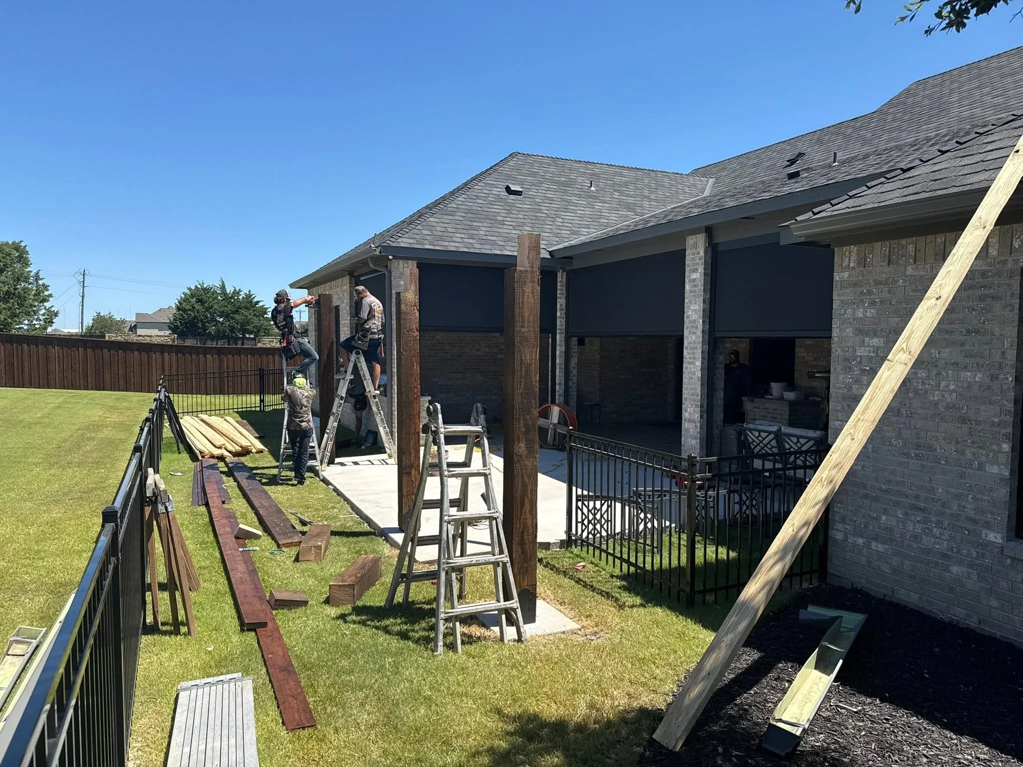 Wooden pergola with black retractable shade screens installed over concrete patio with metal railings