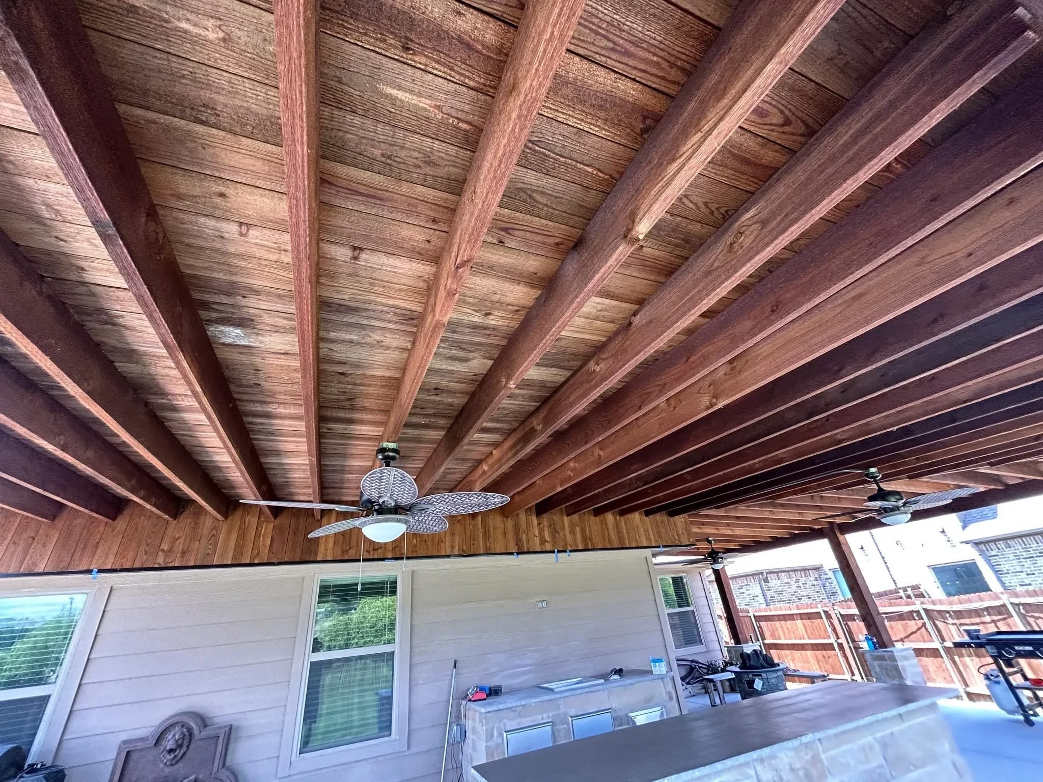 Exposed cedar beam patio ceiling with tongue-and-groove decking and ceiling fans