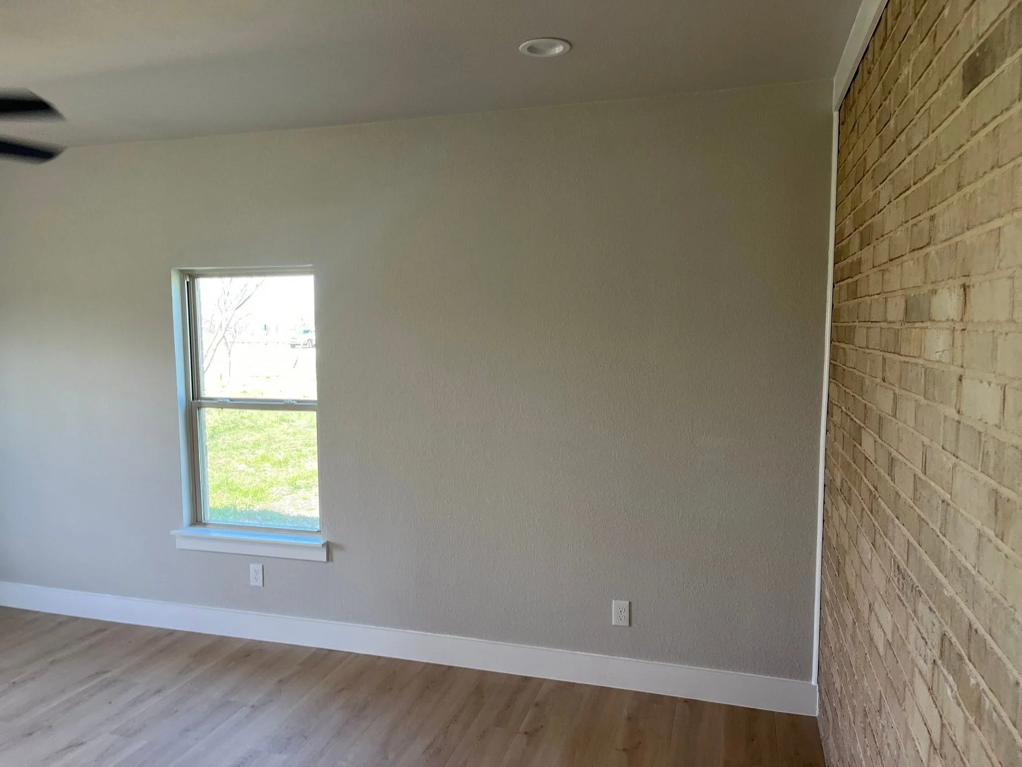 Interior room with finished drywall, white baseboard trim, recessed lighting, and exposed brick accent wall