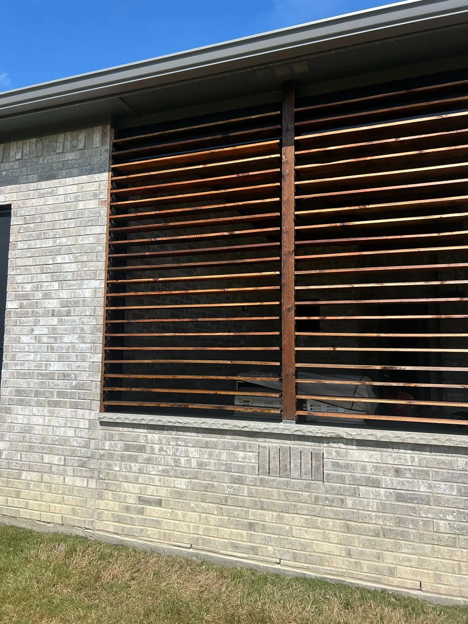 Horizontal wood slat fence with stained timber boards and metal posts on concrete foundation