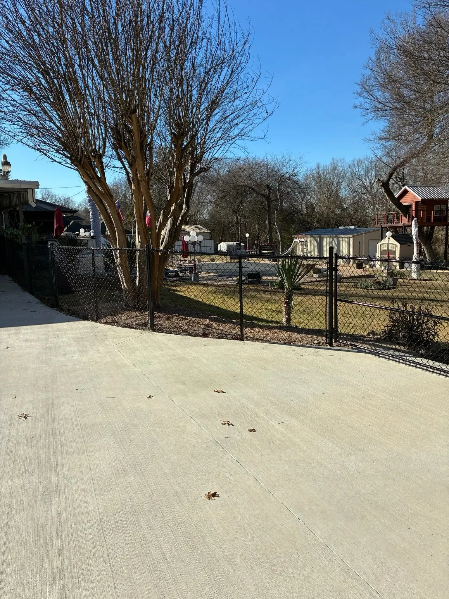 Black chain-link fence with gate, concrete pad, and gravel base installation