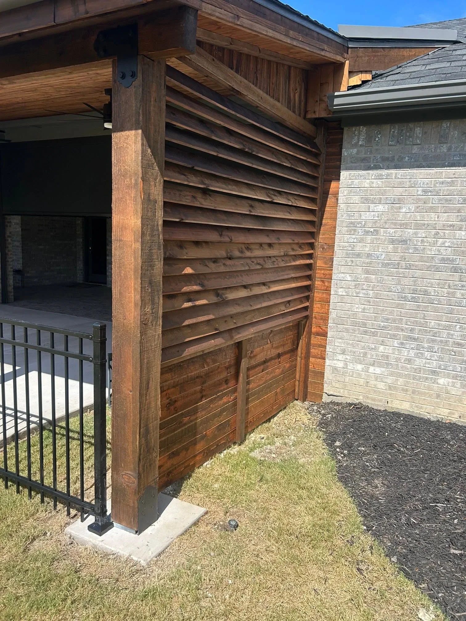 Horizontal louvered wood fence with staggered slats and timber posts