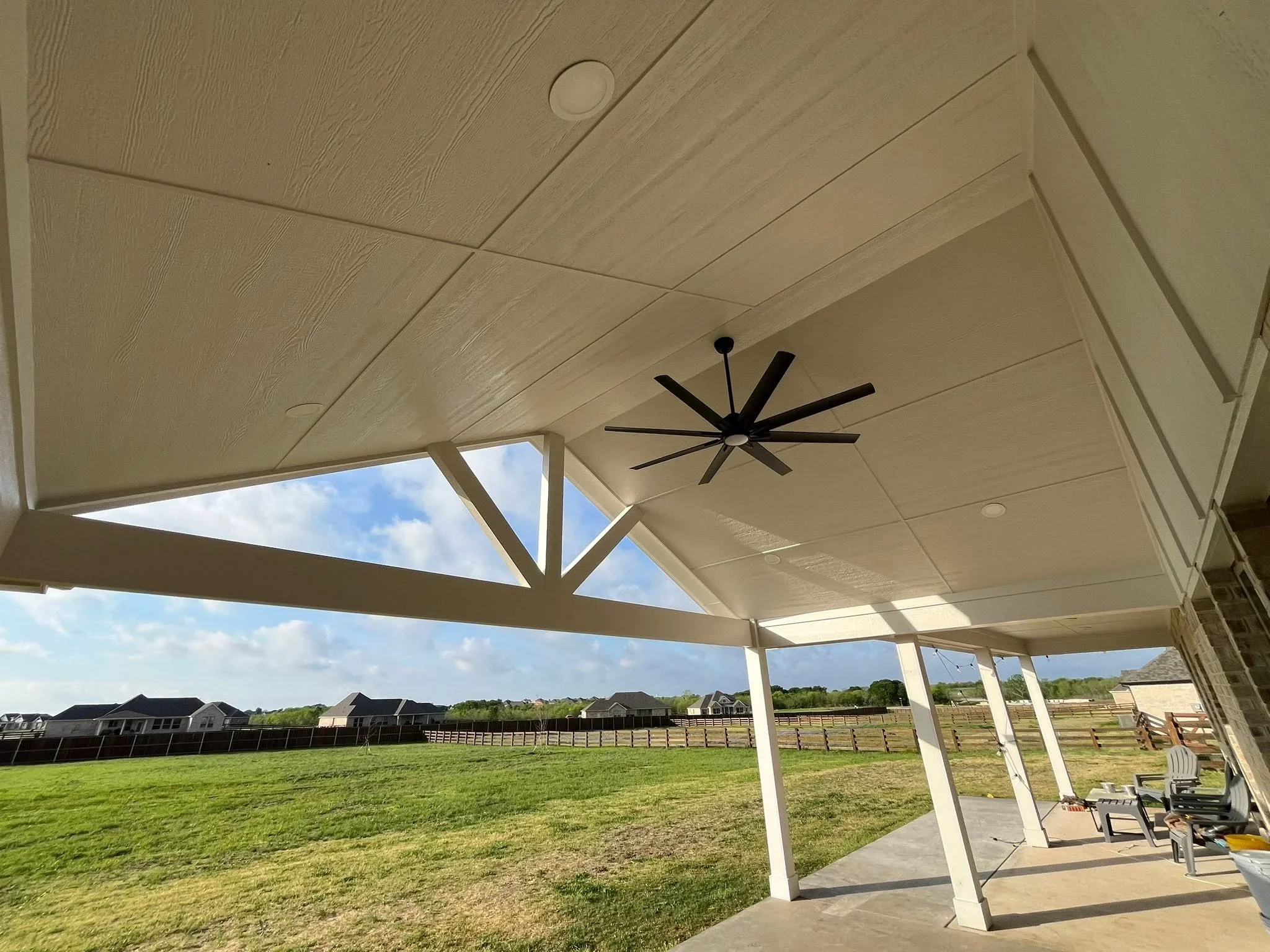 Covered patio with gable roof, composite ceiling, skylight, and ceiling fan overlooking open grounds