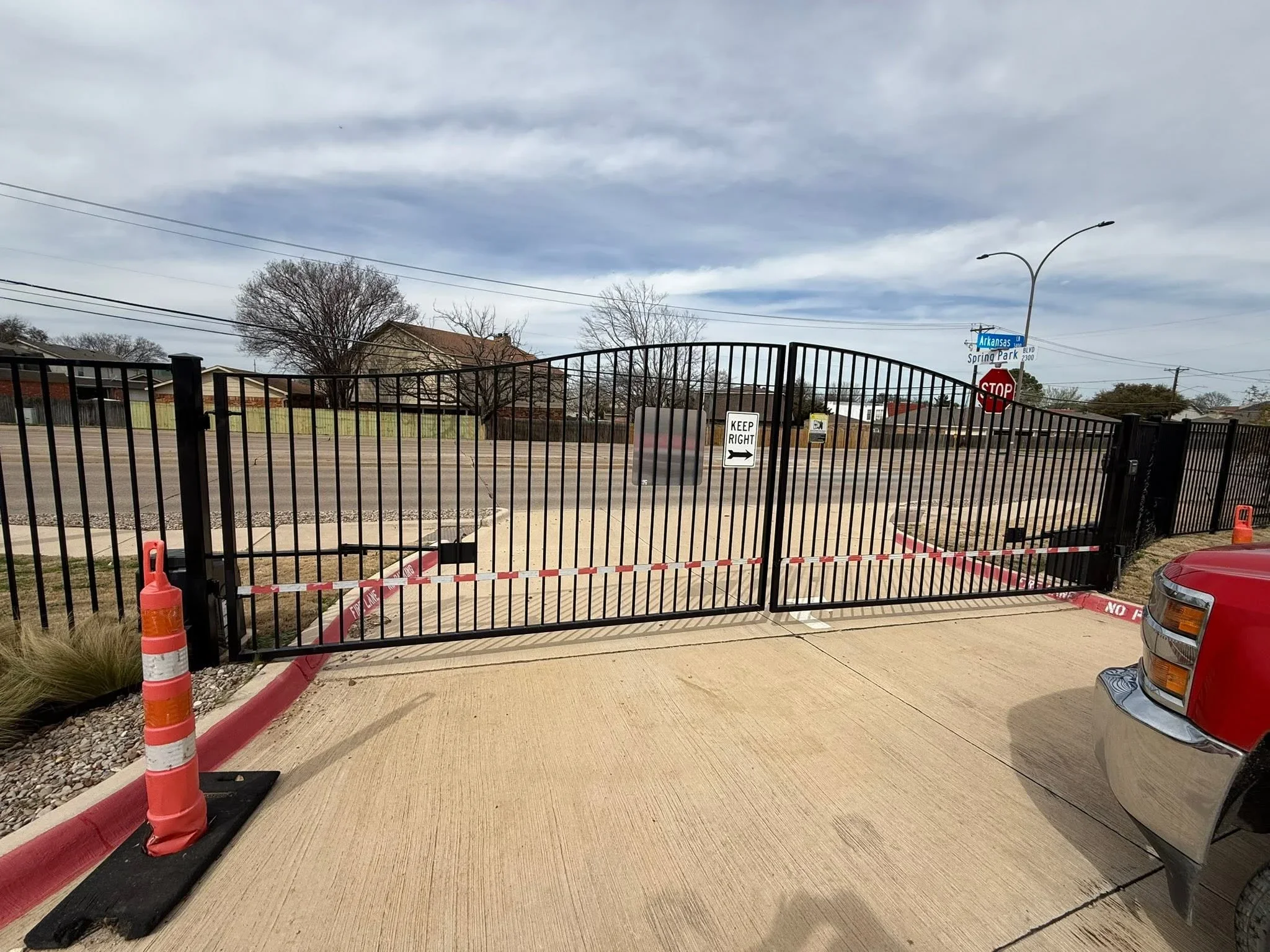 Black steel curved driveway gate with vertical pickets at commercial entrance