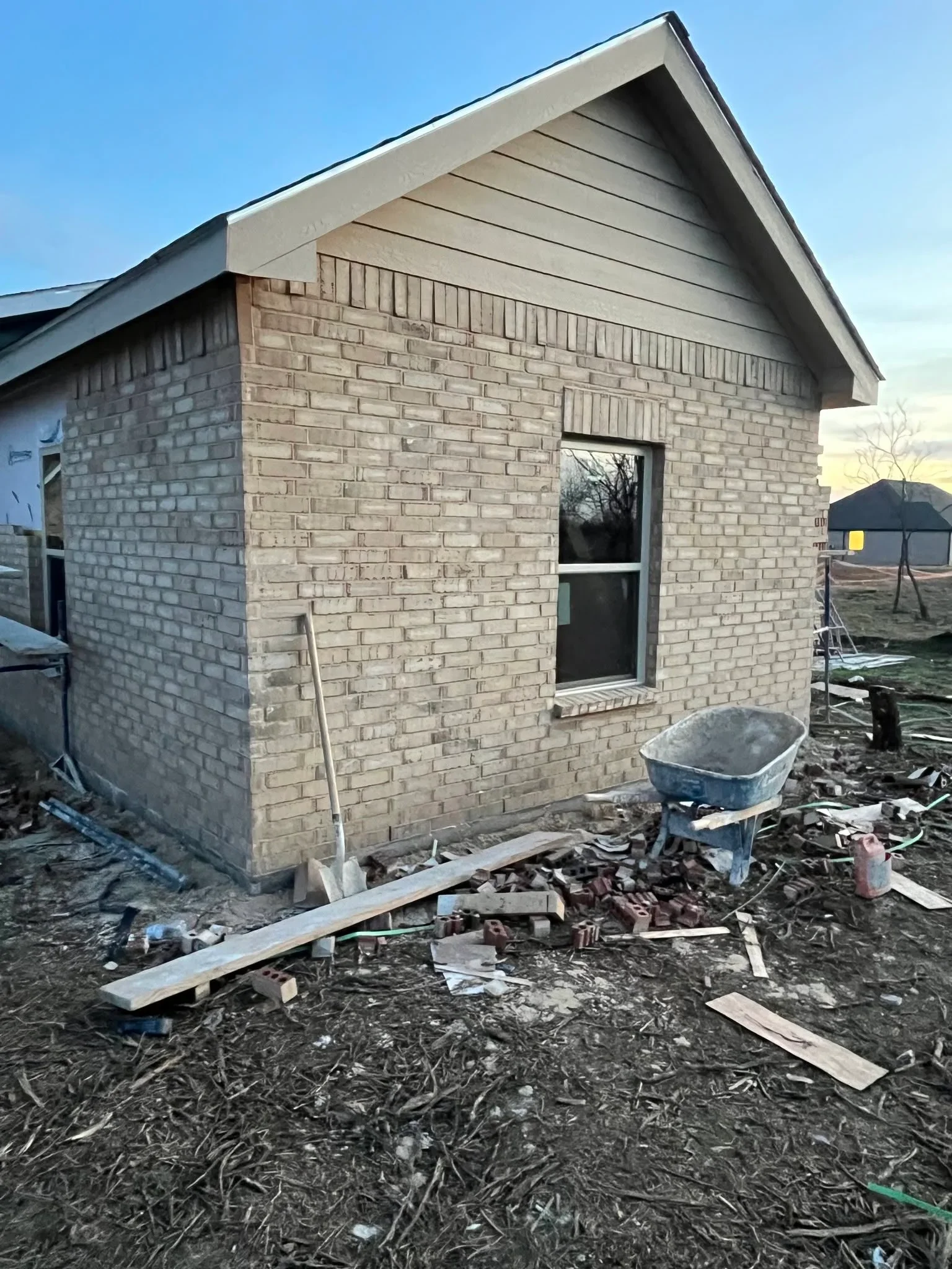 Tan brick addition with new window, pitched roof, and soffit trim installation