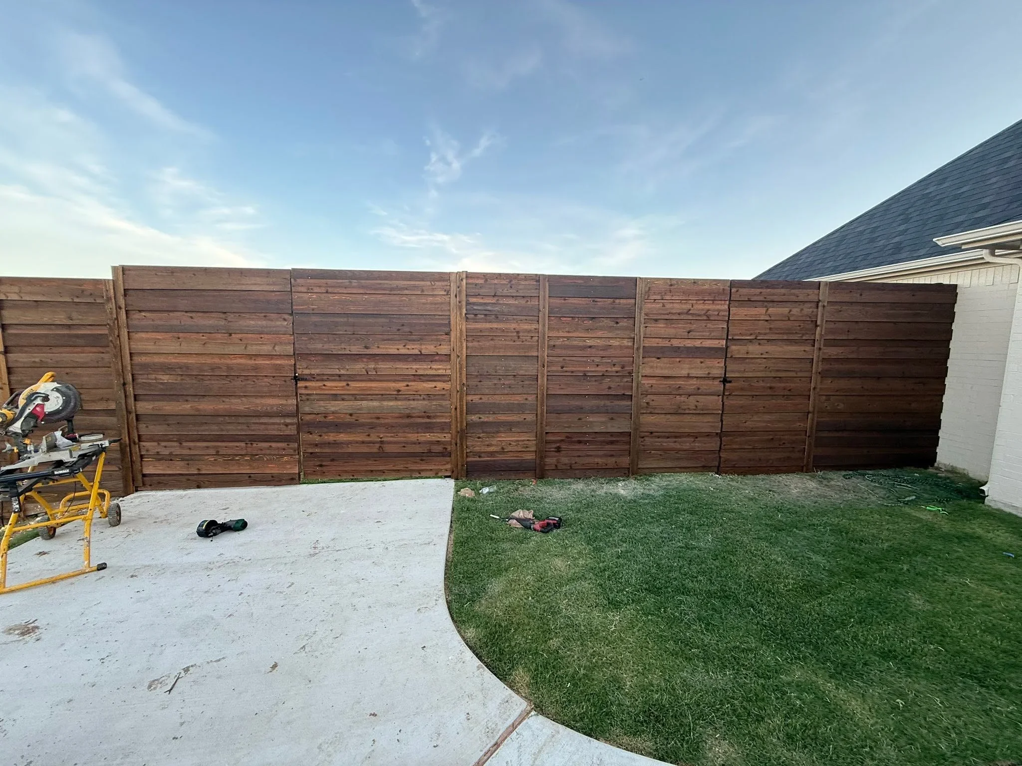 Horizontal wood privacy fence with stained cedar boards and metal posts in residential backyard