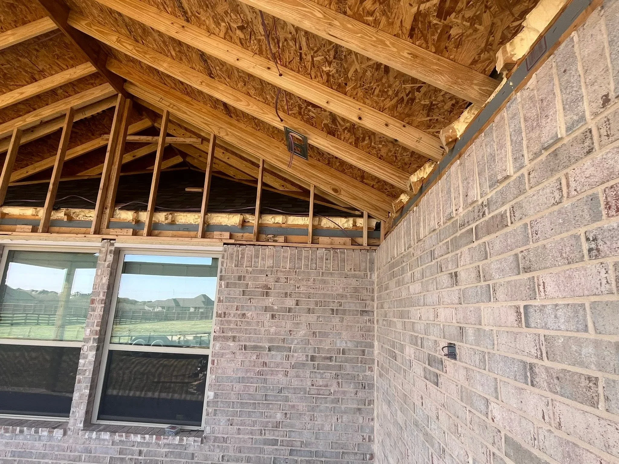 Wood beam framing with OSB sheathing and installed windows in brick wall