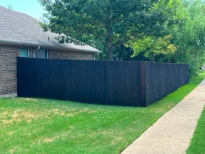 Black vinyl privacy fence with wood-grain texture installed around residential property