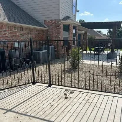 Gray composite deck with black metal vertical railing and posts, attached to brick home