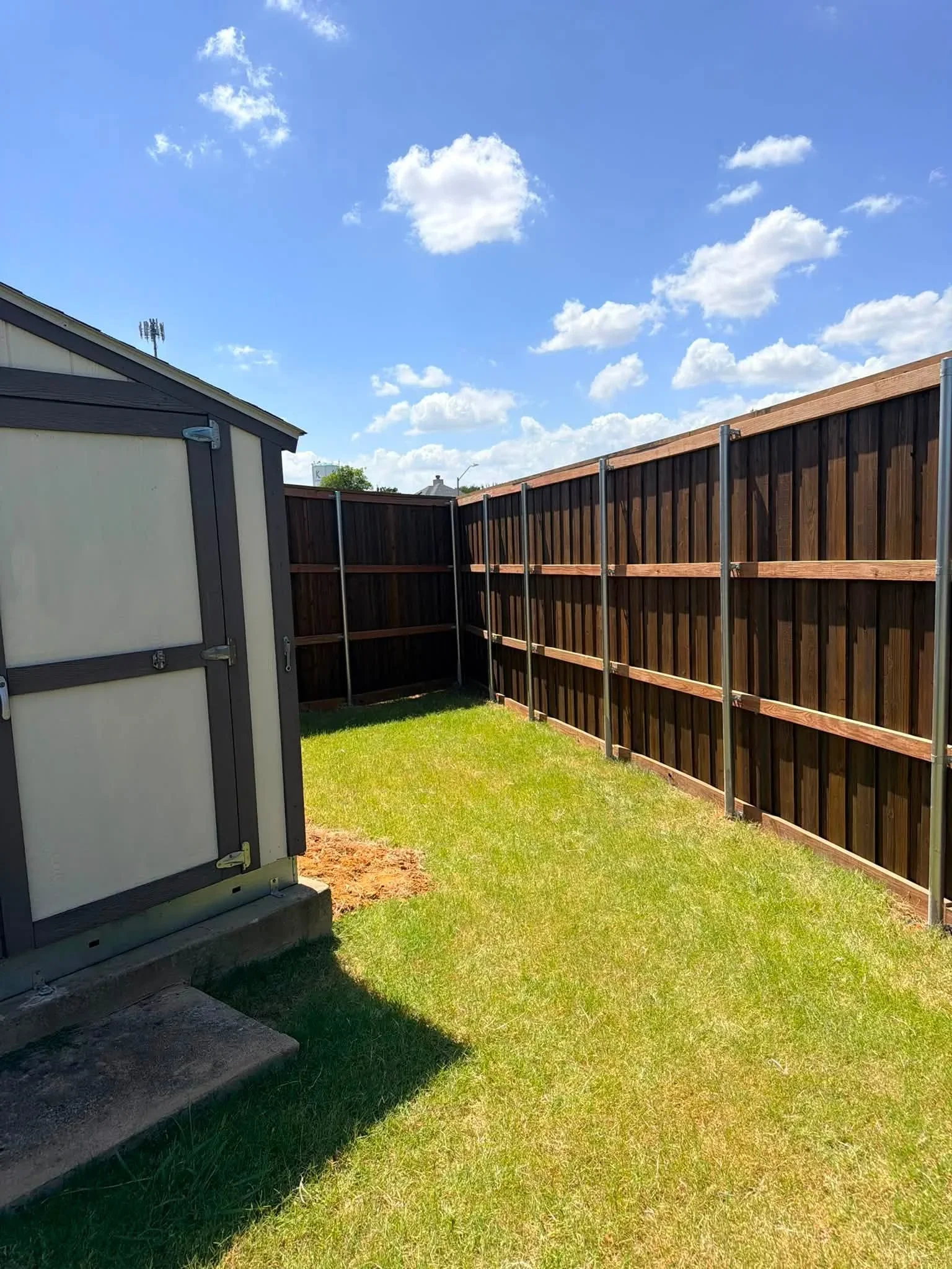Dark wood vertical fence panels with metal frame and horizontal bracing, residential yard enclosure