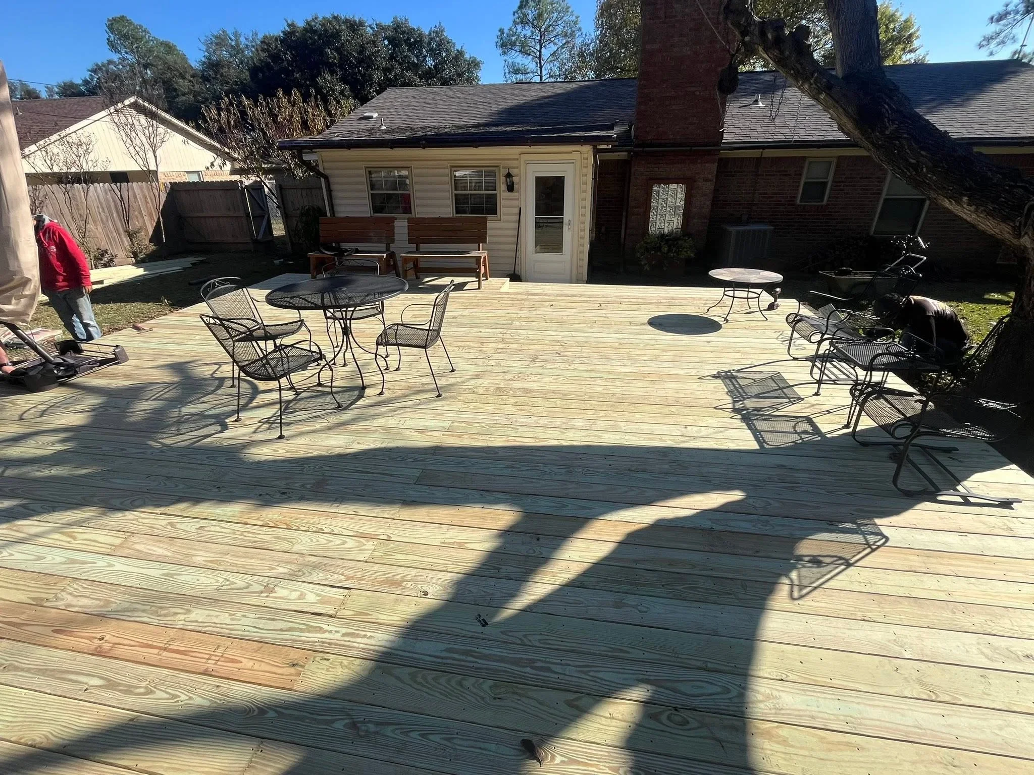 Large pressure-treated wood deck with seating areas and fire pit installation