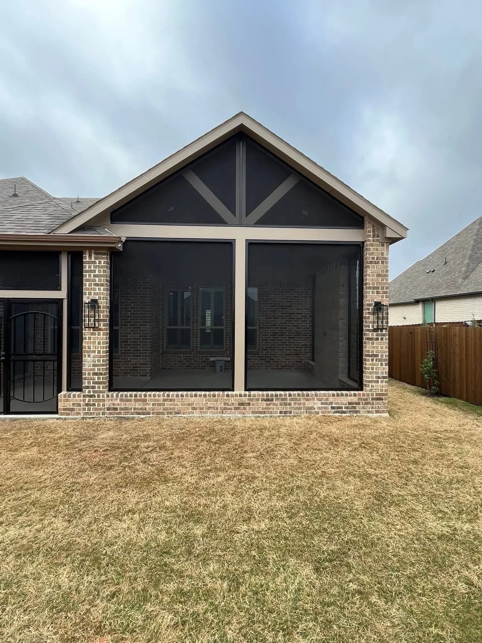 Brick patio with black screen enclosure and decorative gable bracing