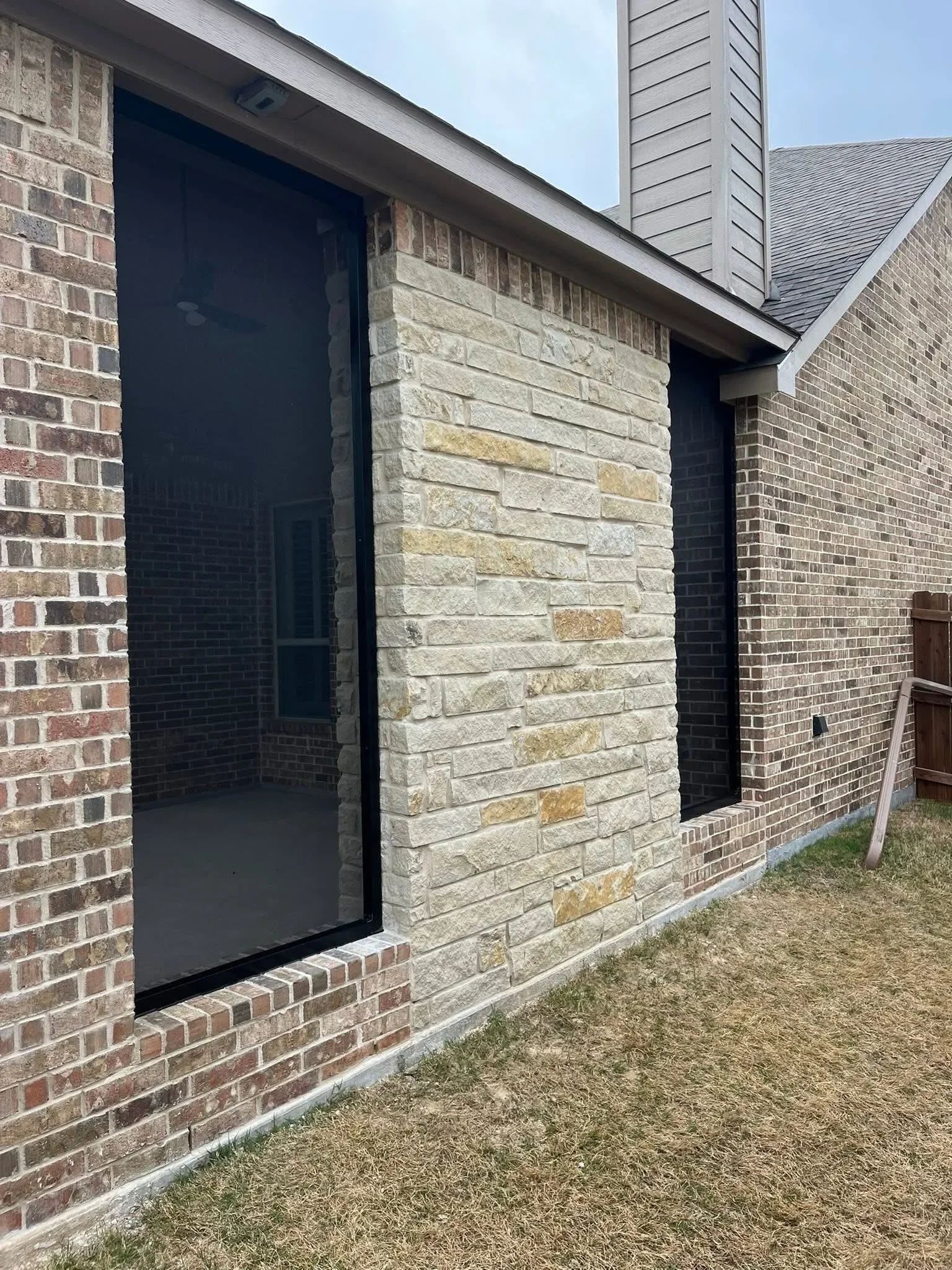 Stone veneer accent wall with horizontal coursing and black entry door on brick home exterior