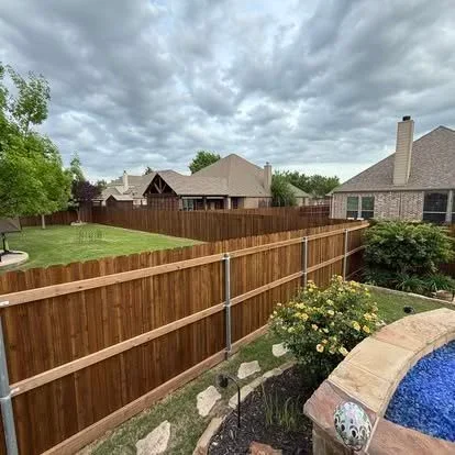 Newly installed wood privacy fence with vertical boards and horizontal rails along residential property