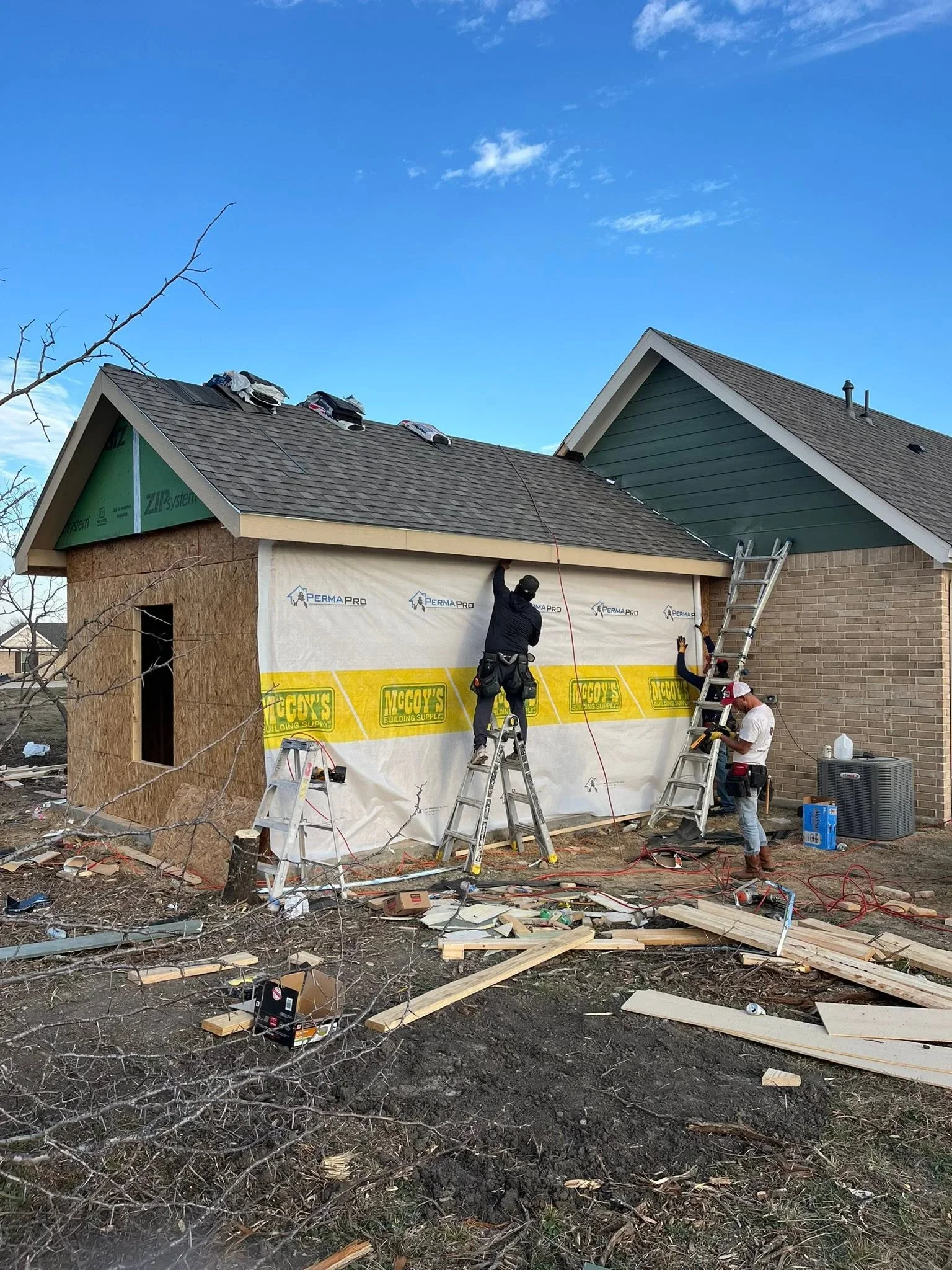 Storm-damaged home restoration with new roof installation and brick and siding repair in progress