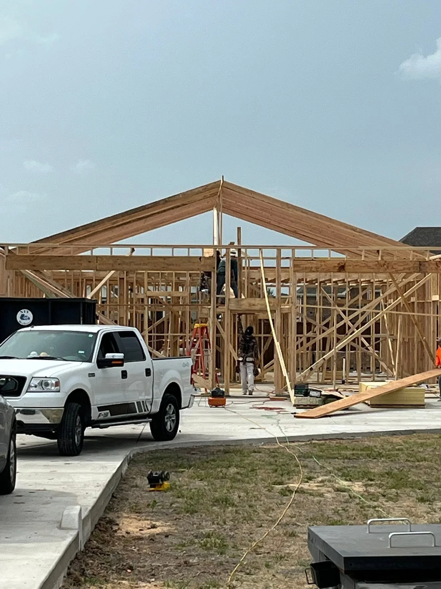 Residential home framing with wood trusses, wall studs, and concrete foundation during construction