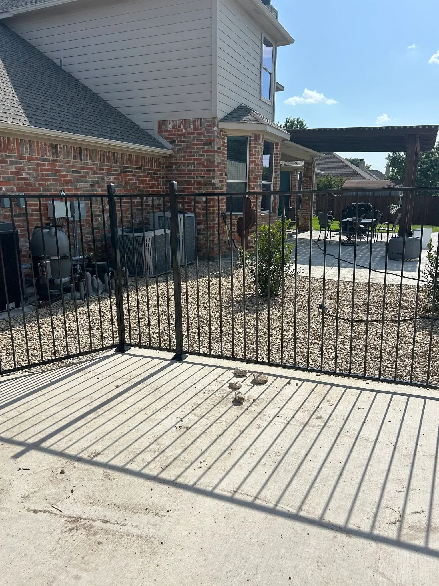 Black aluminum vertical picket fence with gate installed on composite deck beside brick home