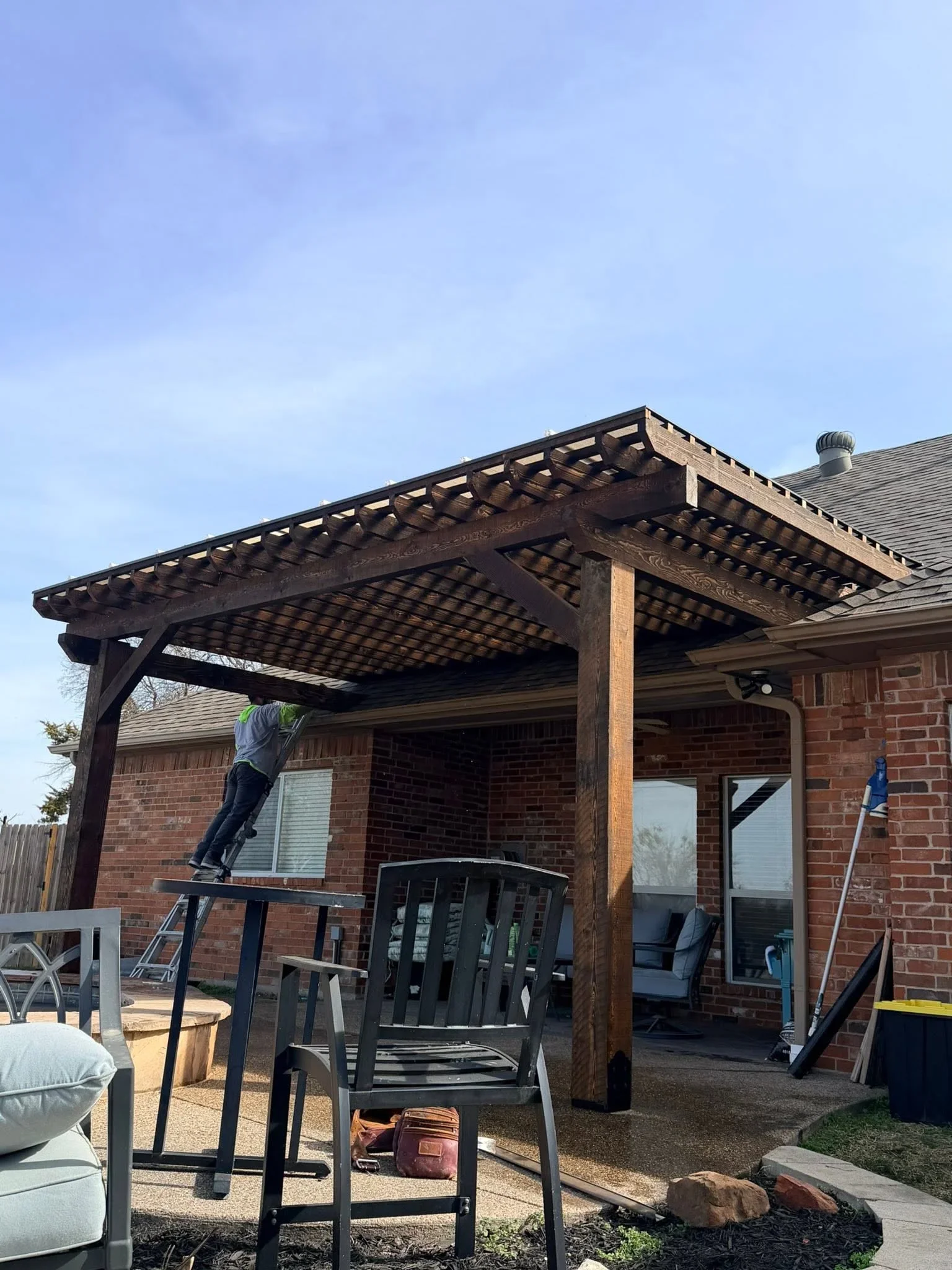 Dark stained wood pergola with lattice roof over patio, timber posts and beams